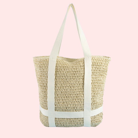 Woven straw tote bag with light blue straps on a pink background