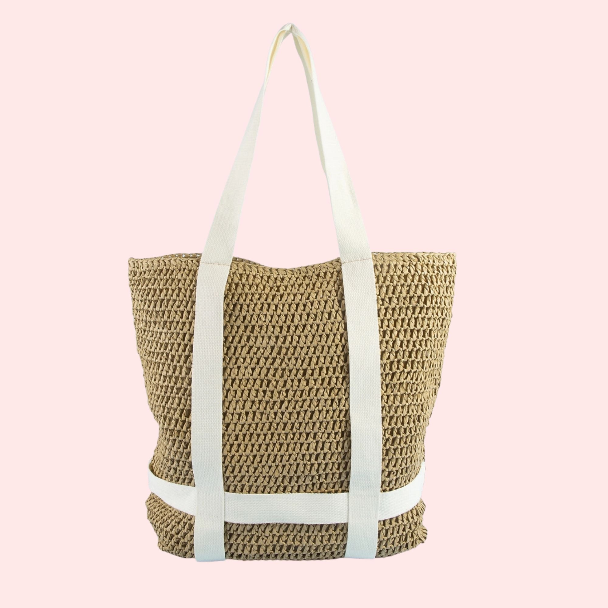 Woven straw tote bag with white straps on a pink background