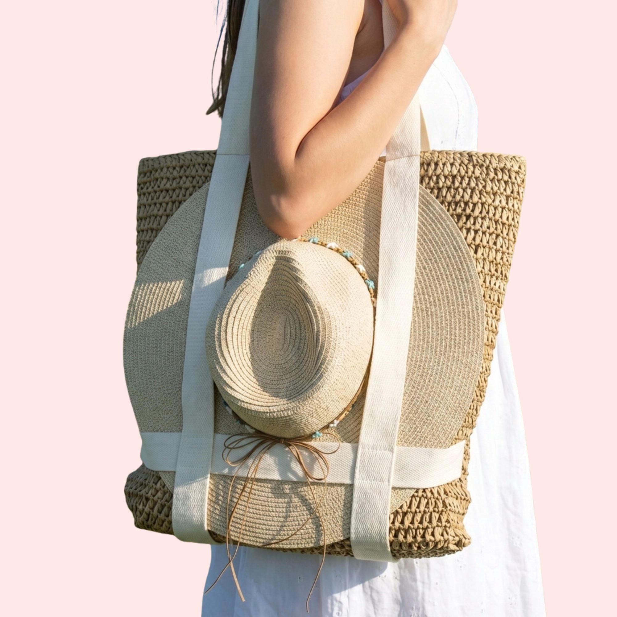 Woven tote bag with a straw hat on a light pink background